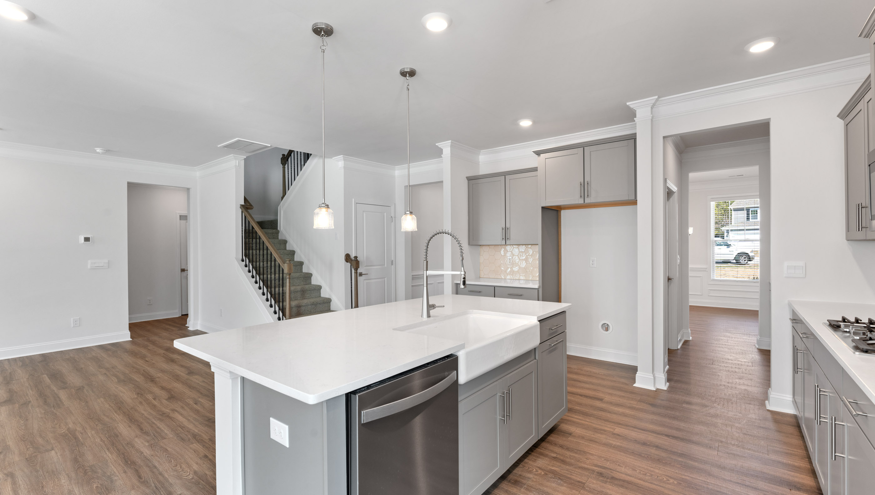 View of gourmet kitchen with quartz center island, stainless steel appliances, and recessed and pendulum lighting.