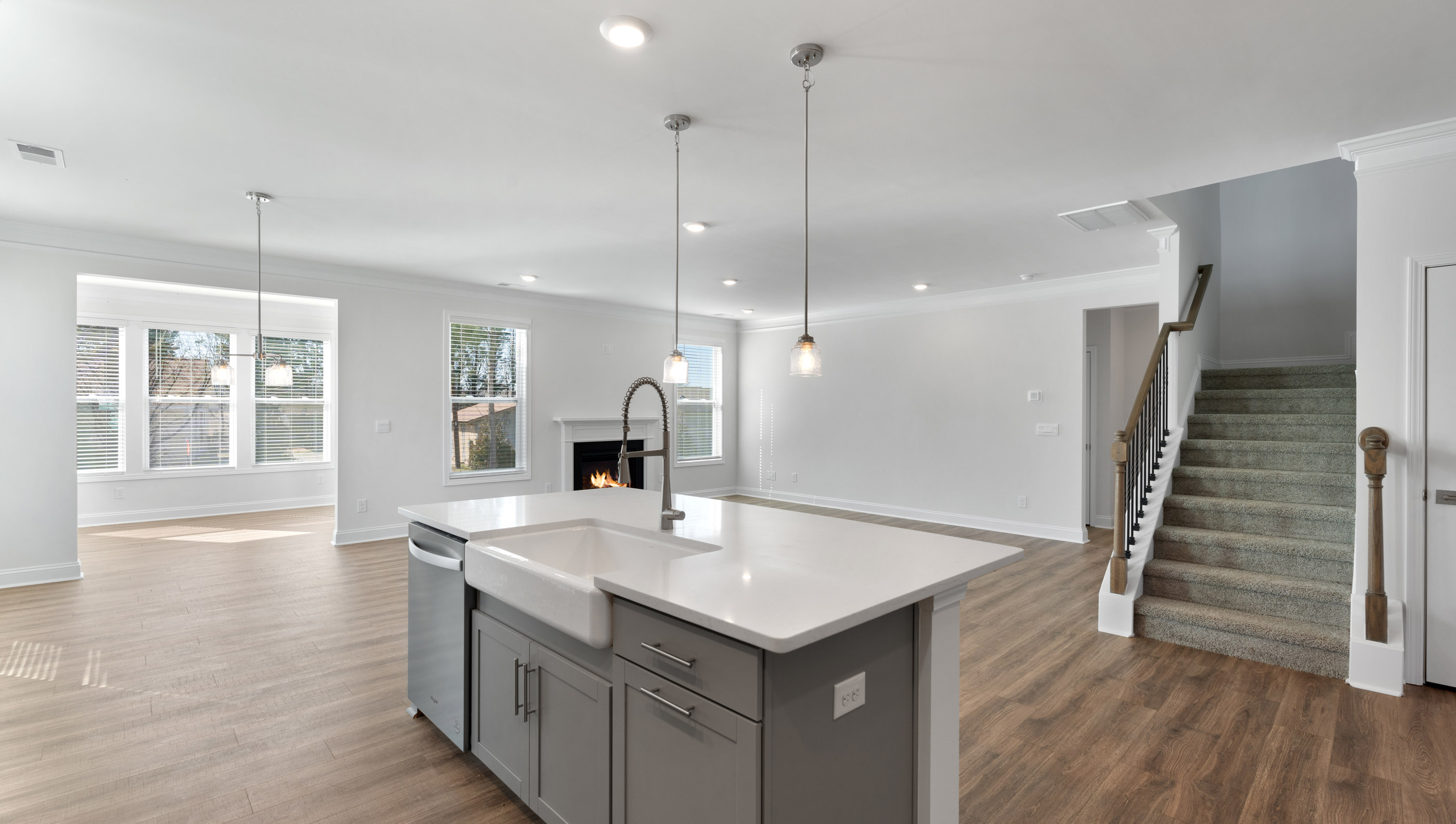 View of gourmet kitchen with quartz center island, stainless steel appliances, and recessed and pendulum lighting.