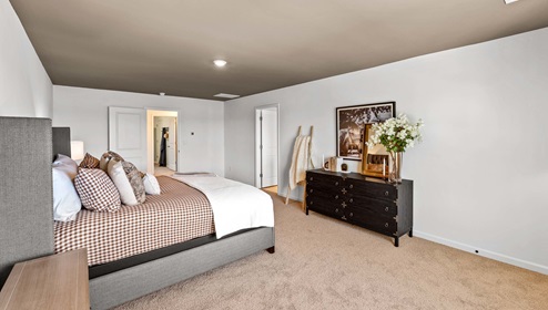 Primary bedroom with carpet and window.