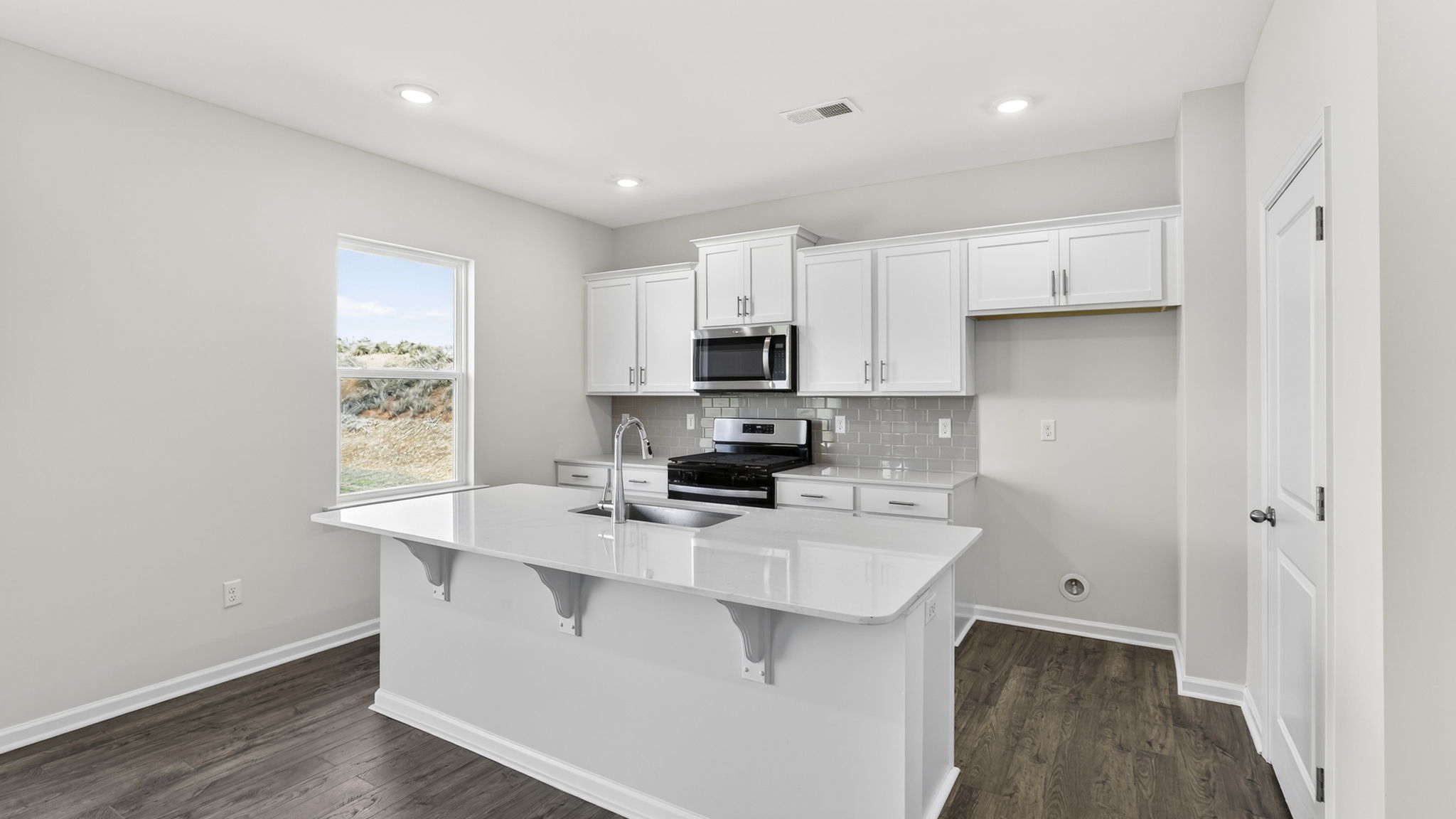 Kitchen and island with quartz counter tops and stainless steel appliances.
