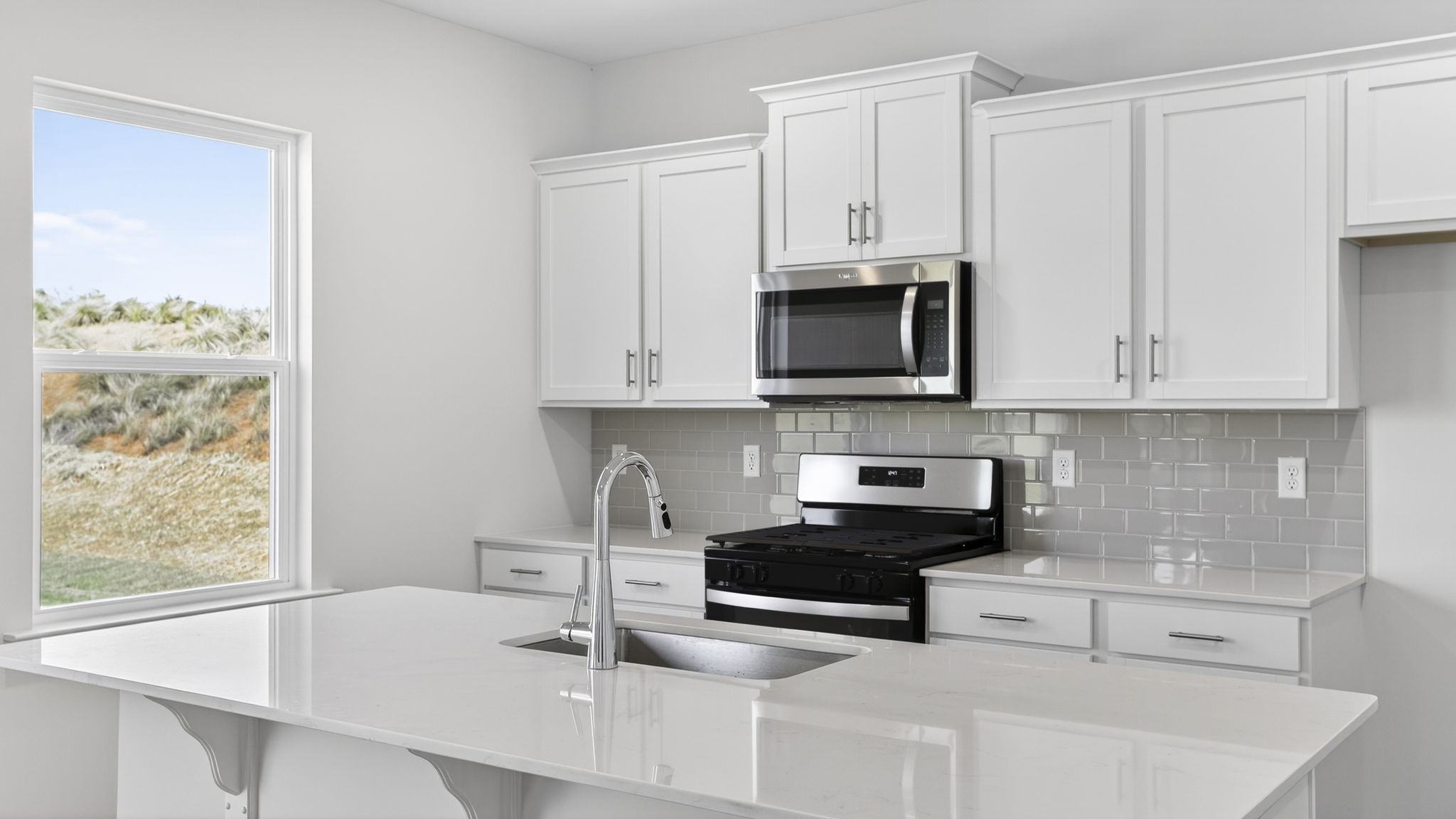 Kitchen and island with quartz counter tops and stainless steel appliances.