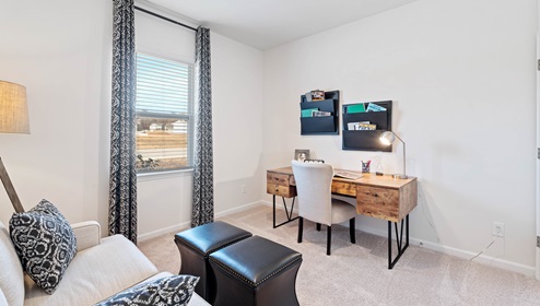 Bedroom used as office with carpet and window.