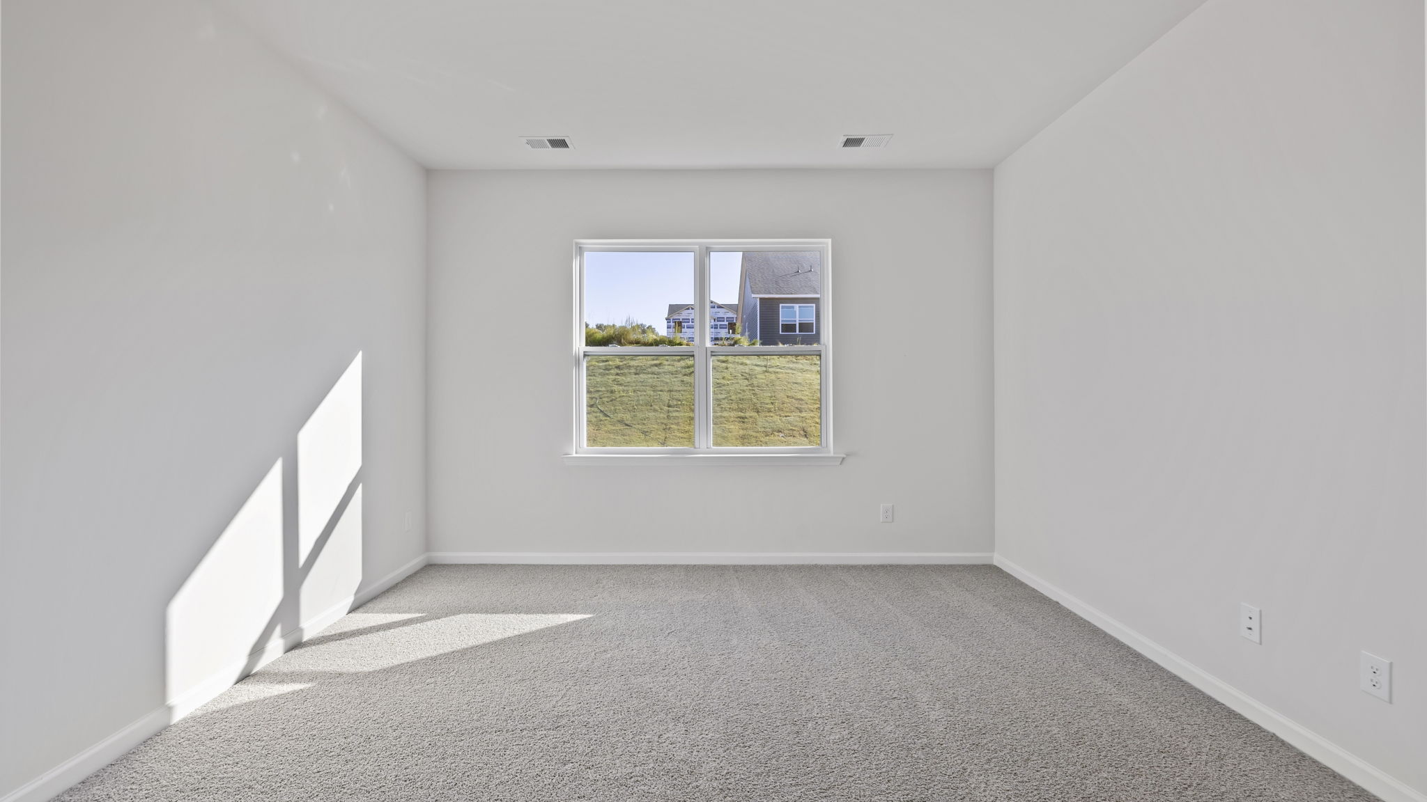 Primary bedroom with carpet and window.