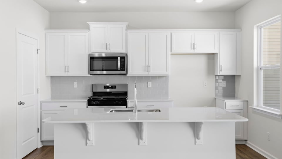 Kitchen and island with quartz countertops and stainless steel appliances.