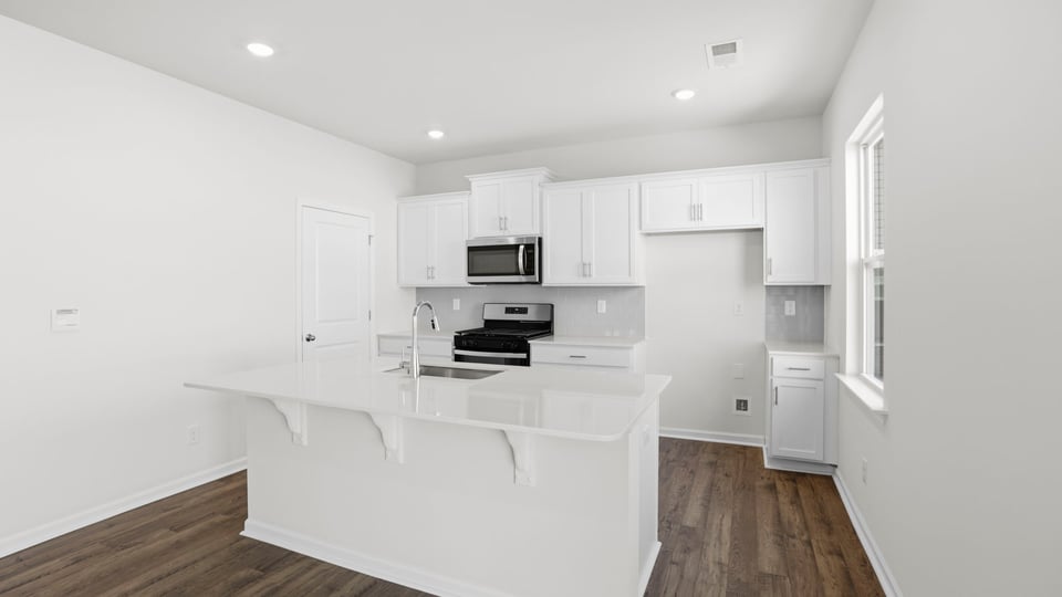 Kitchen and island with quartz countertops and stainless steel appliances.