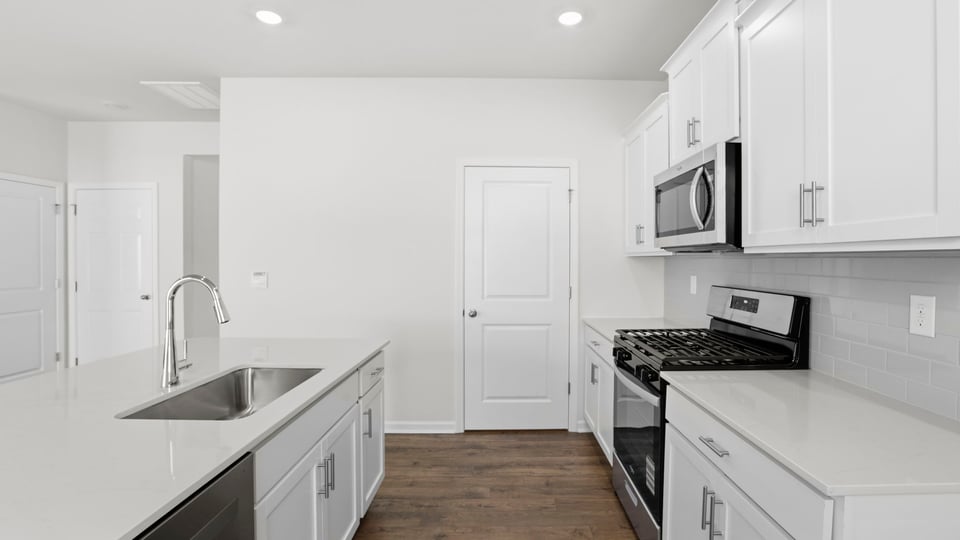 Kitchen and island with quartz countertops and stainless steel appliances.