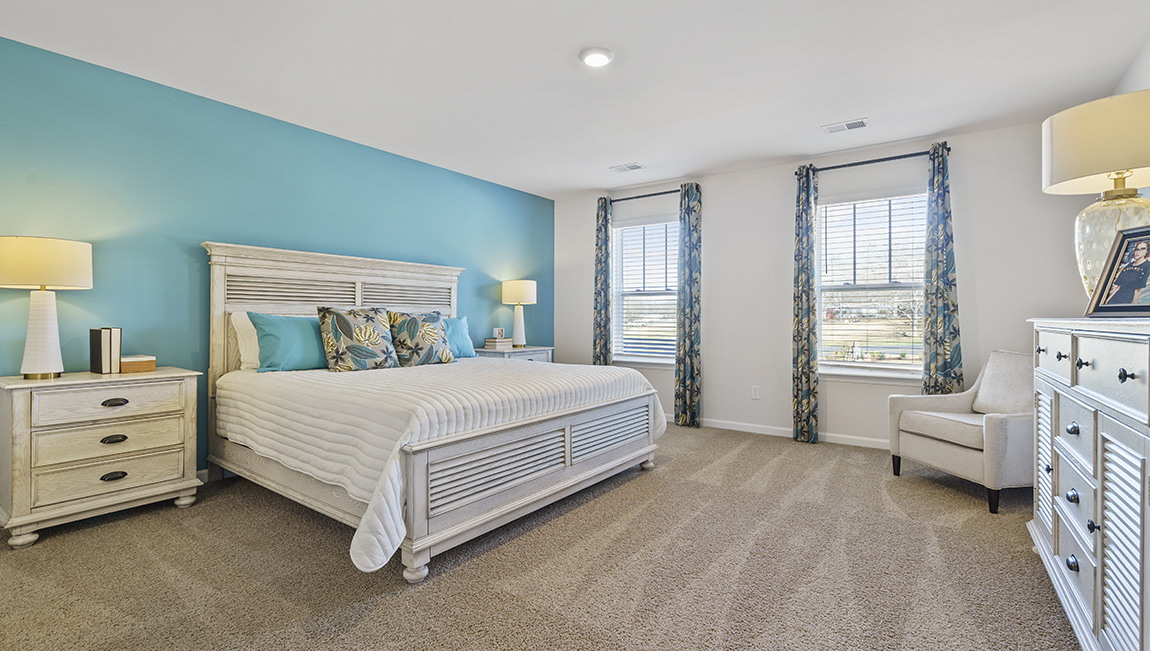 Primary bedroom with carpet and window.