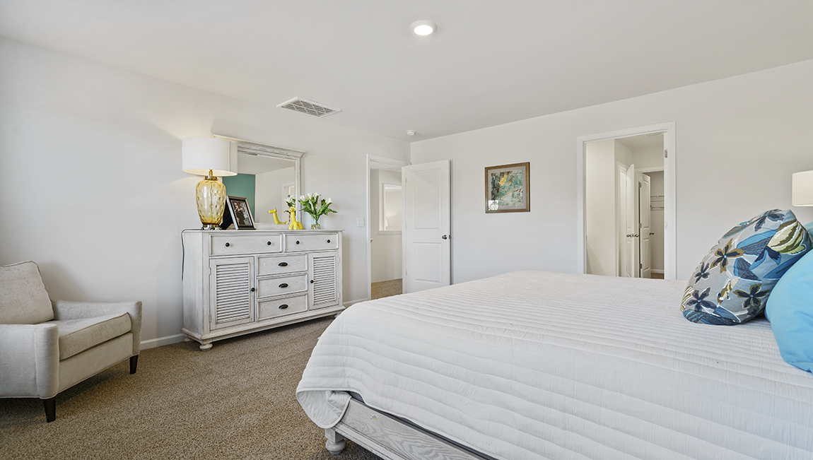 Primary bedroom with carpet and window.