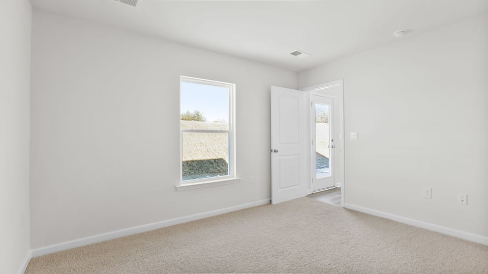 Primary bedroom with carpet and windows.