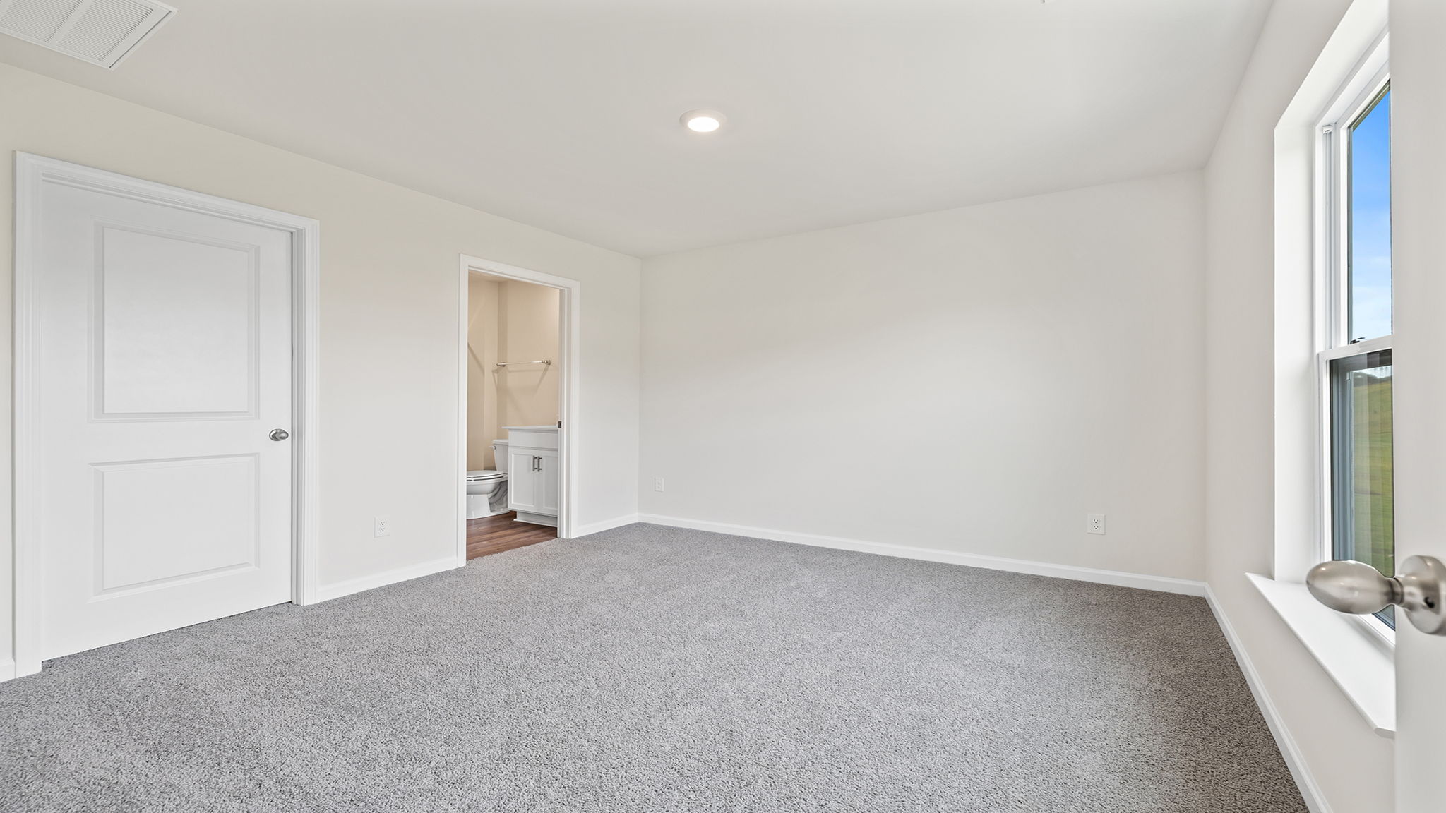 Primary bedroom with windows and carpet.