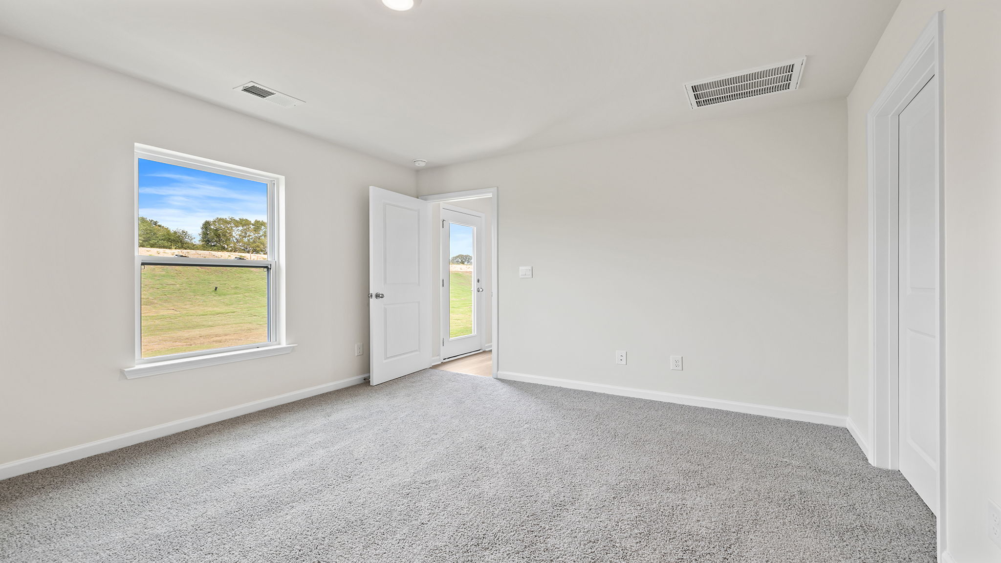 Primary bedroom with large window and carpet.