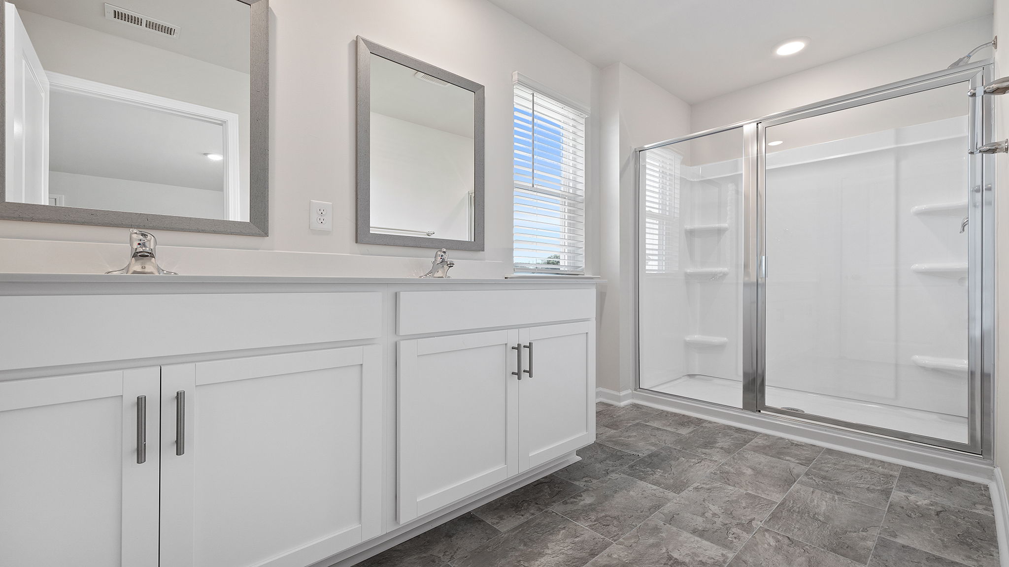 Primary bathroom with dual sink vanity and walk-in shower.