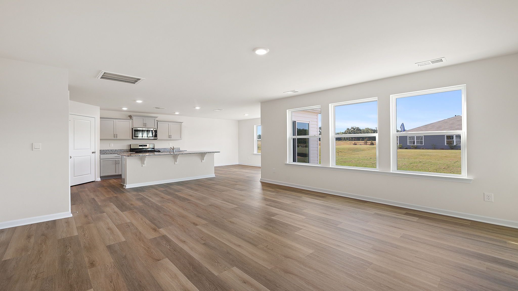 View from family room of the wall of windows and the kitchen and dining area.