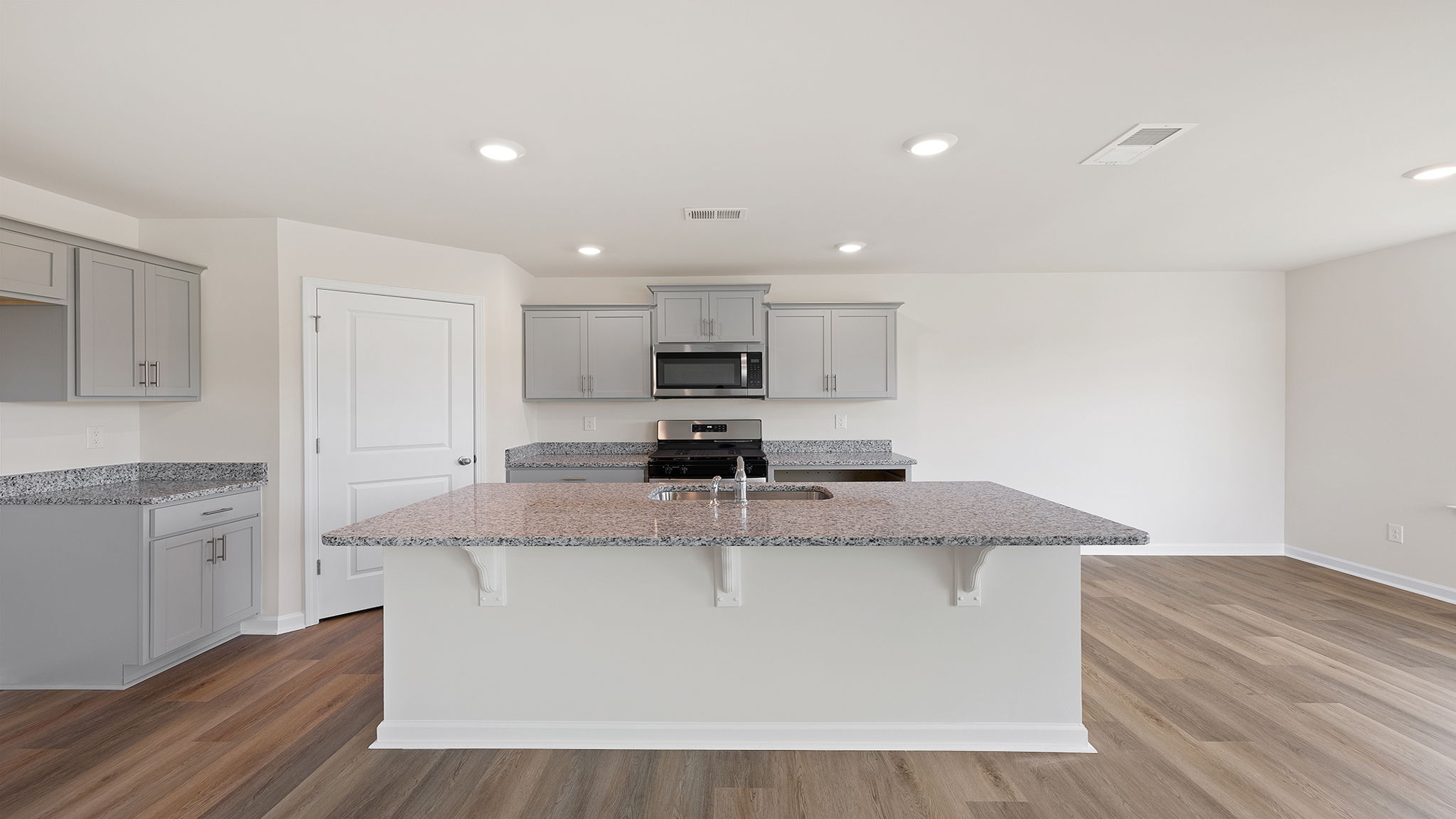 Kitchen is open to both the family and dining areas featuring recessed lighting.