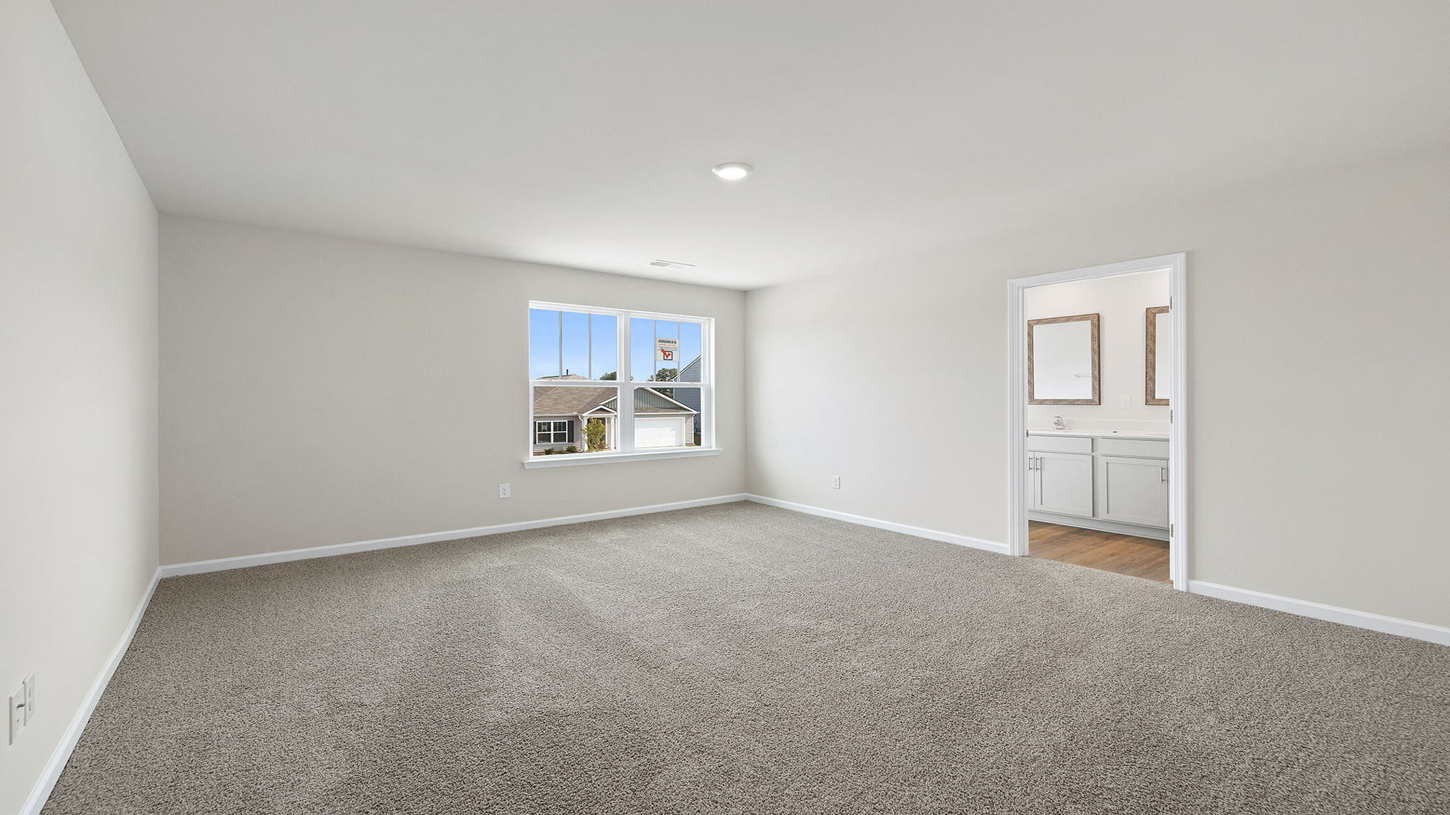 View of primary bedroom with large window and entrance into primary bath.