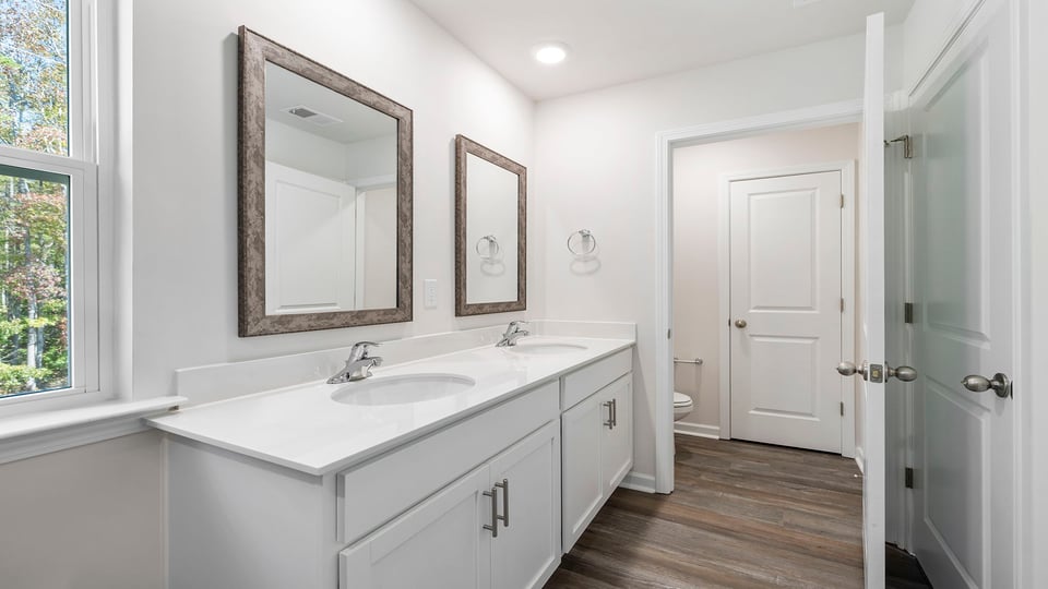 Primary bathroom with dual sink vanity and mirrors.