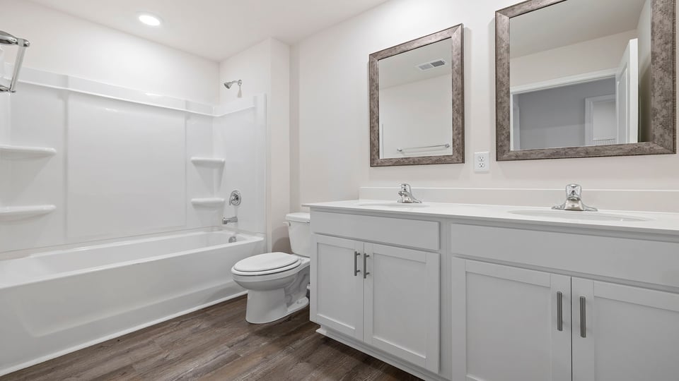 Hall bathroom with dual sink vanity and combination shower / tub.