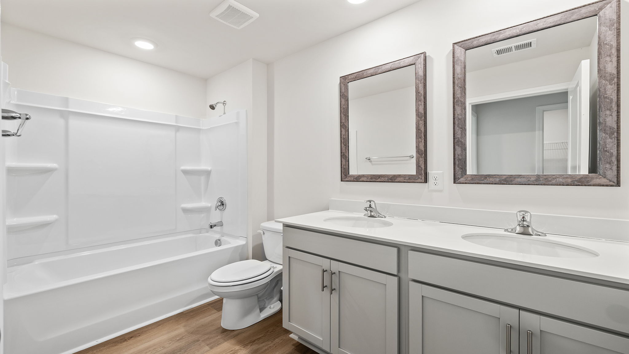 Hall bathroom with dual sink vanity and combination shower / tub.
