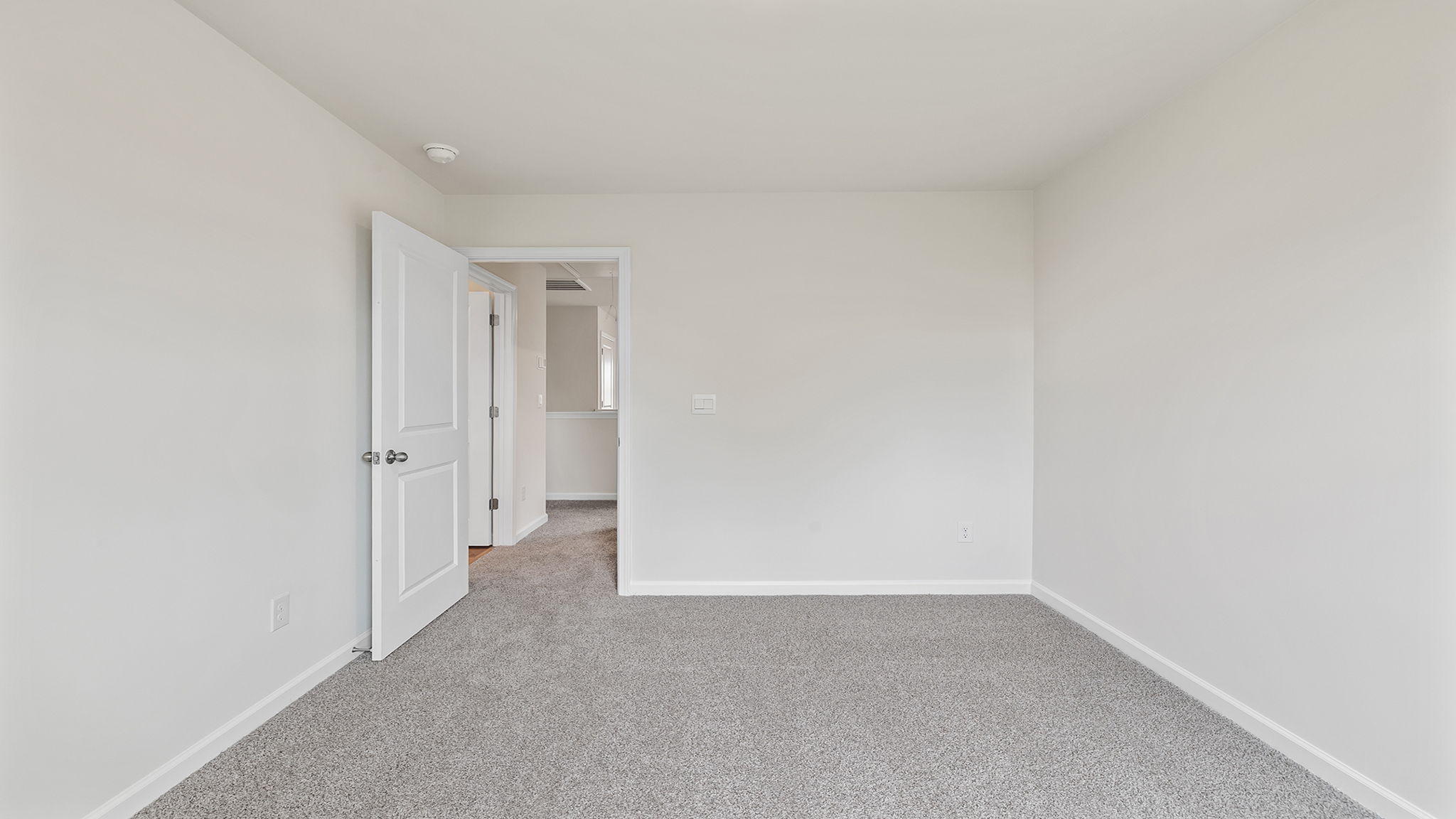 Primary bedroom with carpet and window.
