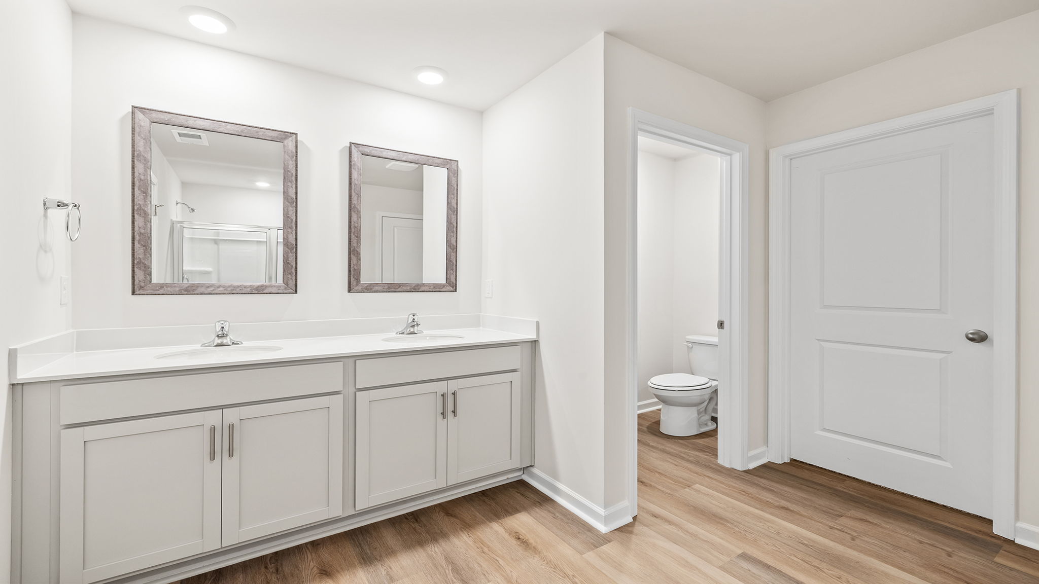 Primary bathroom with dual sink vanity and mirrors.