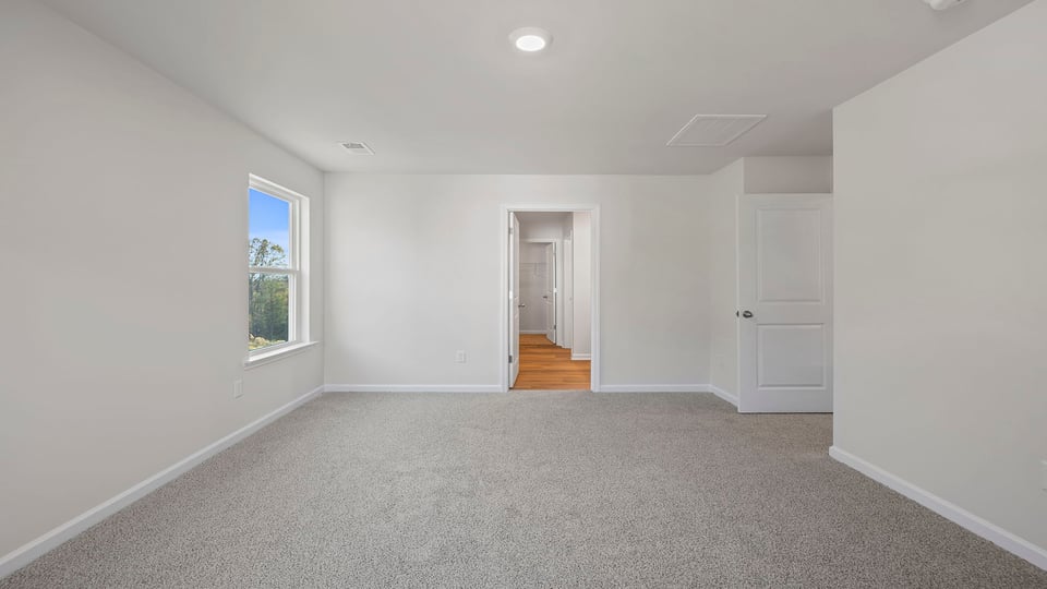 Primary bedroom with carpet and windows.