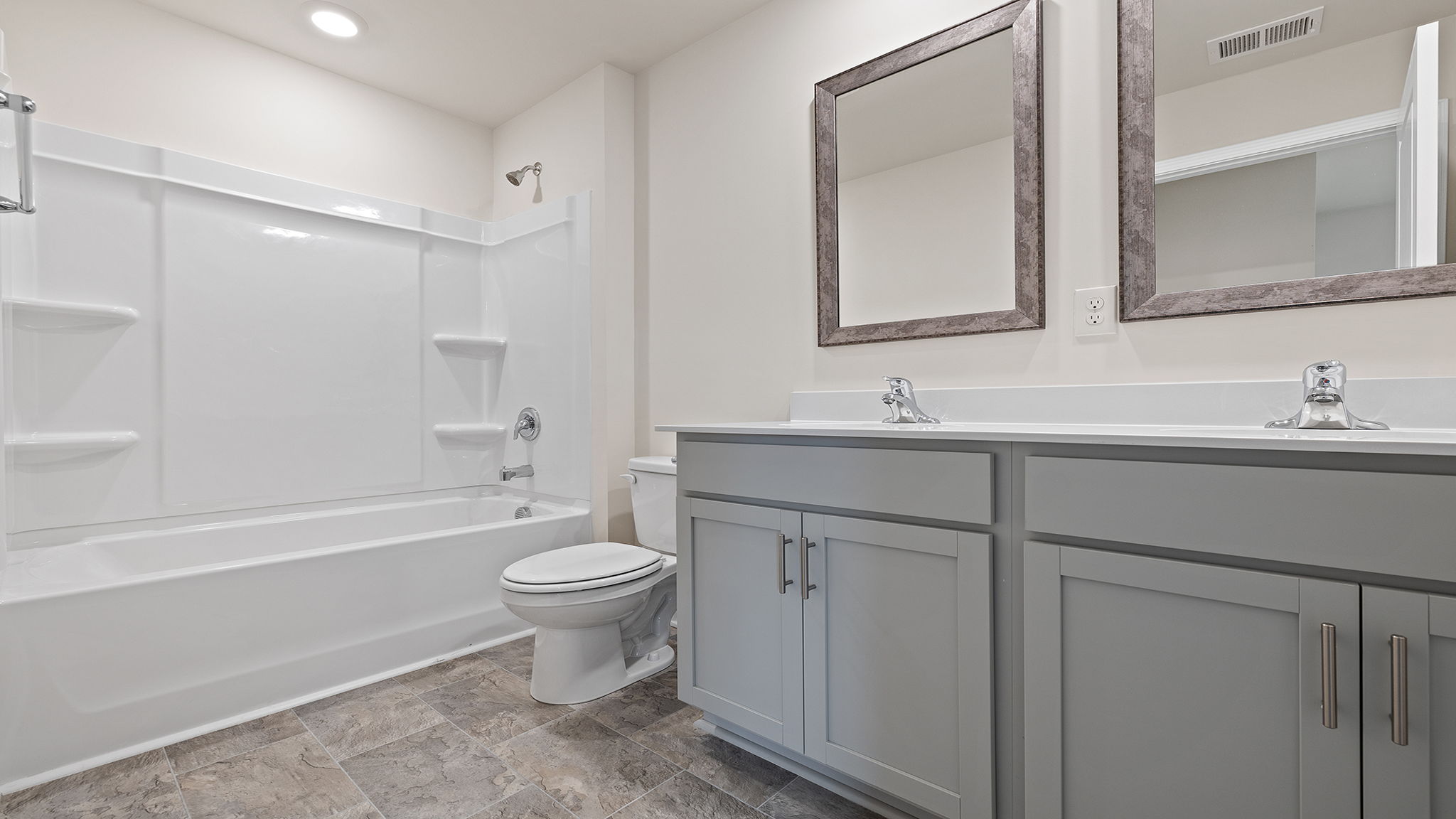Hall bathroom with dual sink vanity and combination shower / tub.