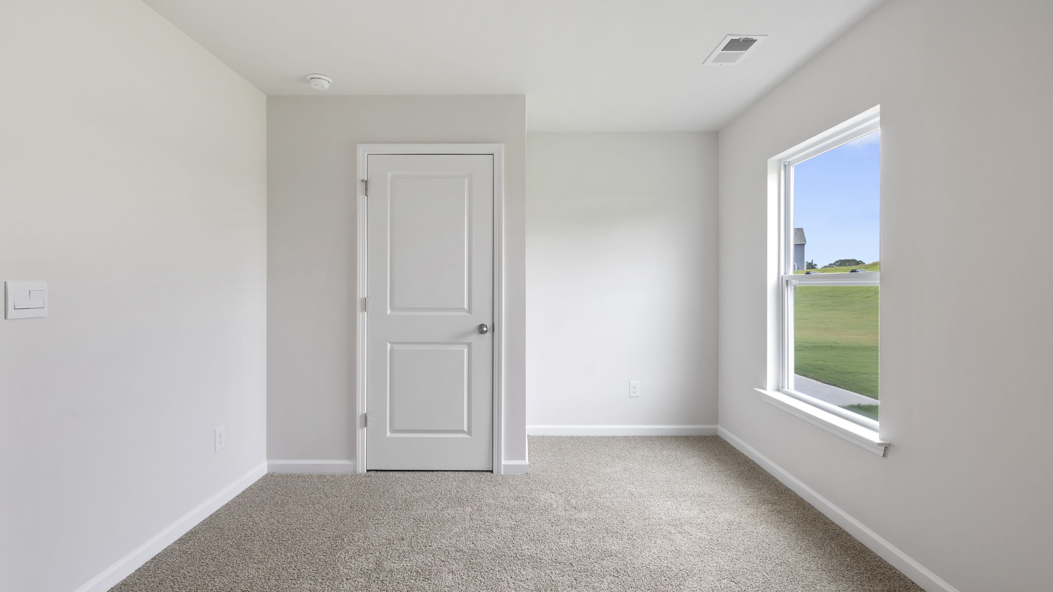 Bedroom on main level with carpet and window.
