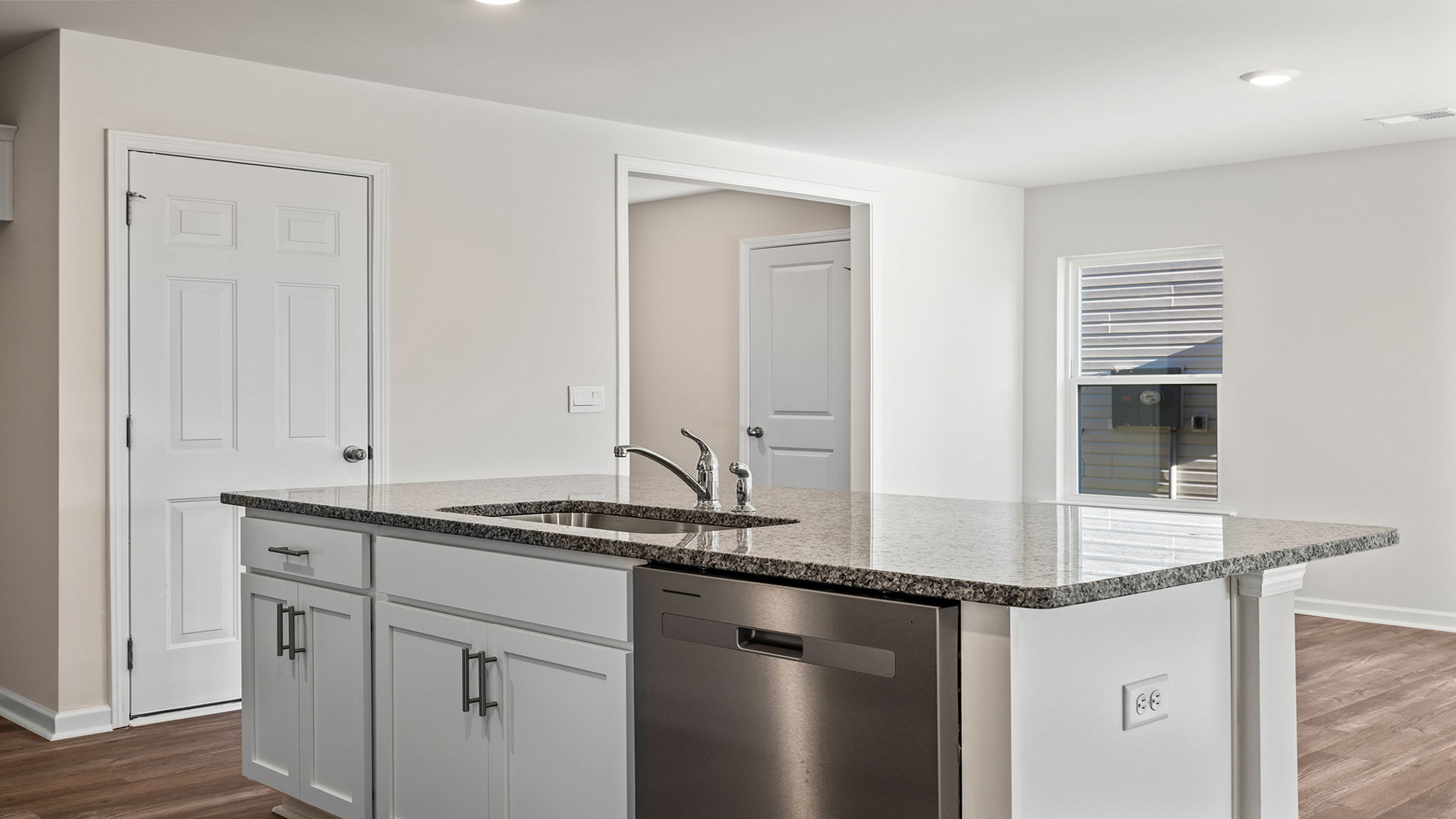 Kitchen island overlooks the dining area and hosts the sink and dishwasher.