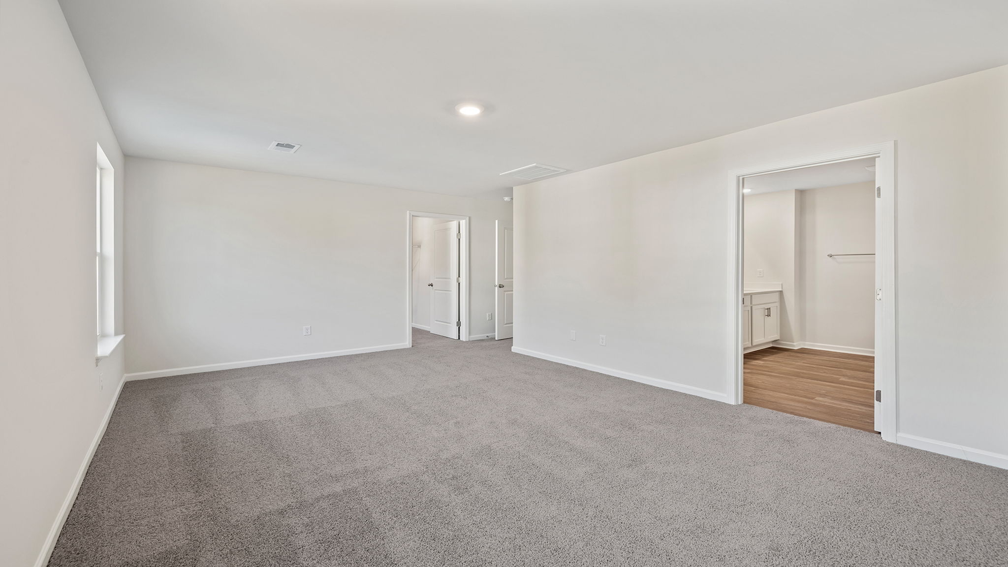 Primary bedroom with carpet and windows.