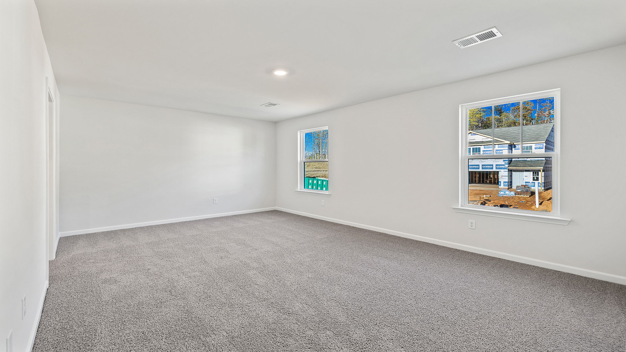 Primary bedroom with carpet and windows.