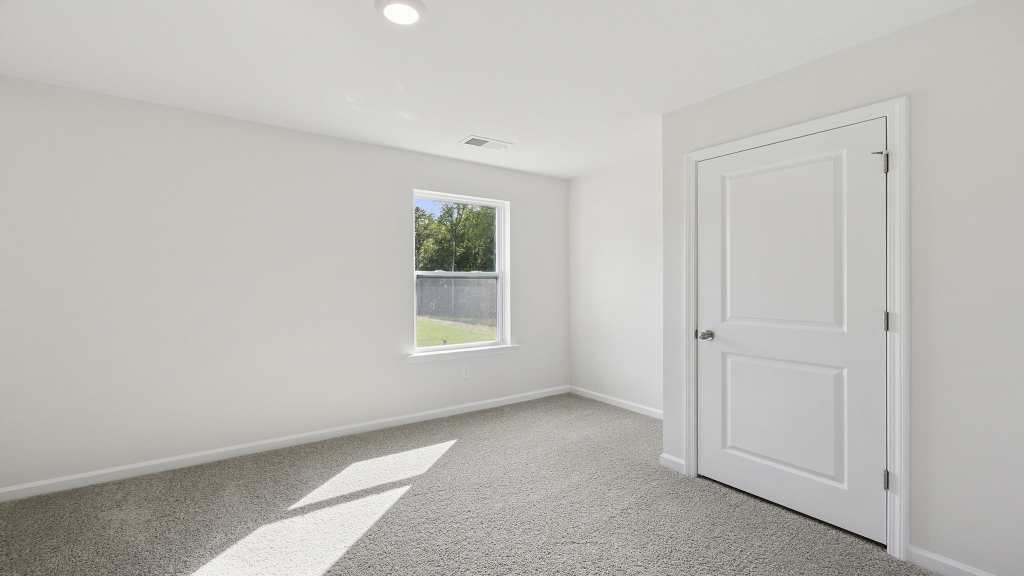 Bedroom with window and carpet on the main level.