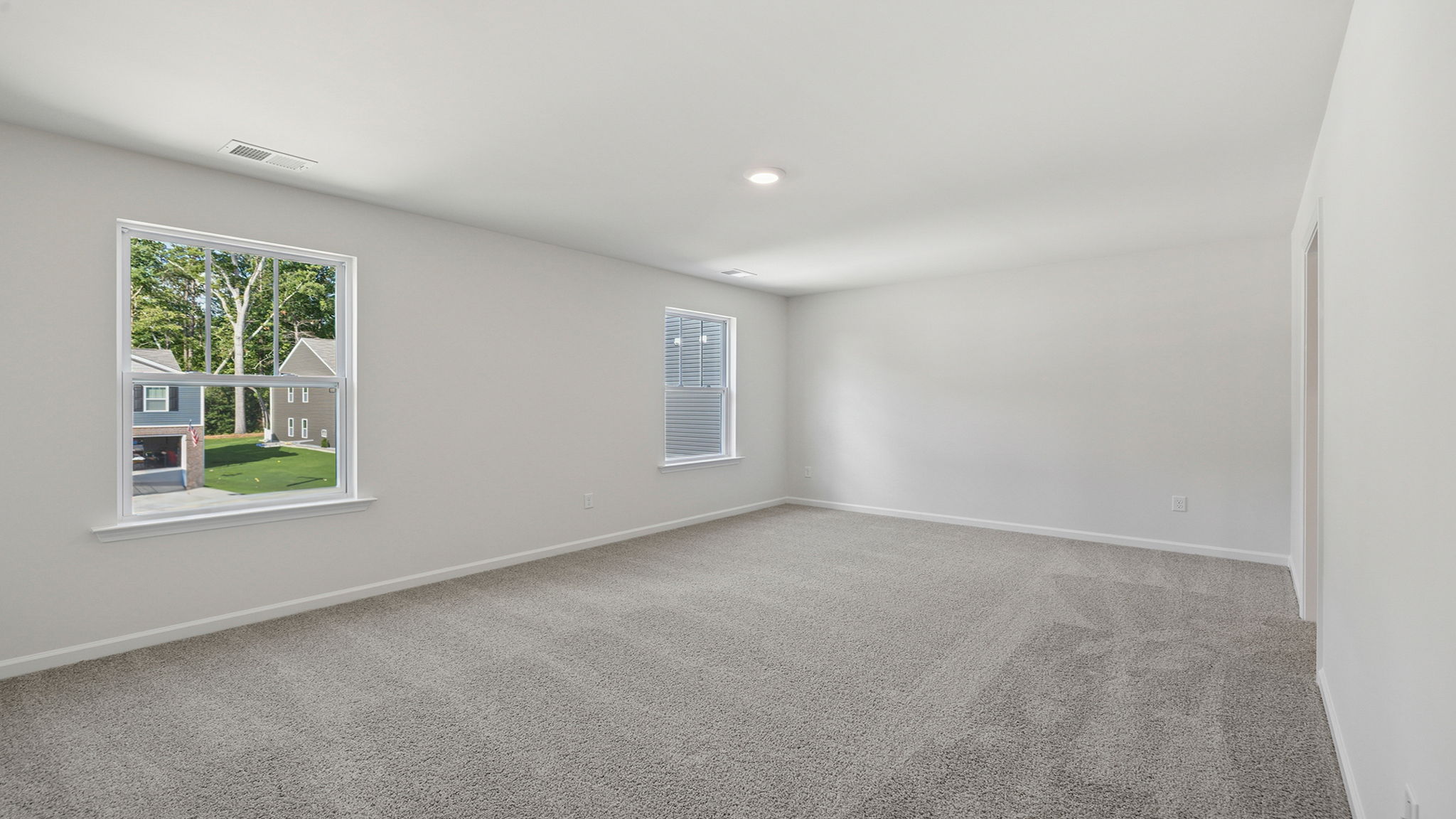 Primary bedroom with carpet and windows.