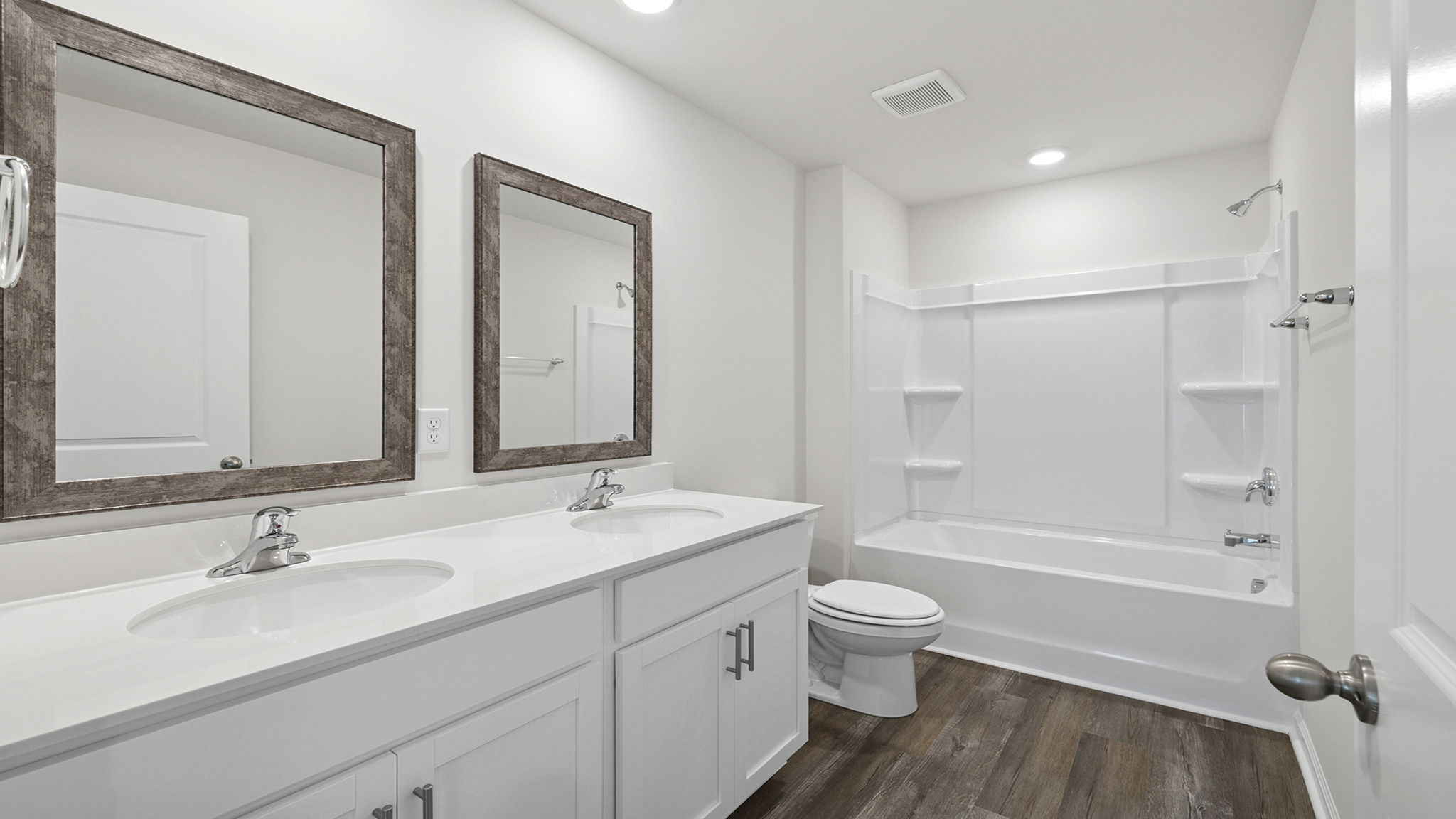 Hall bathroom with dual sink vanity and combination shower / tub.