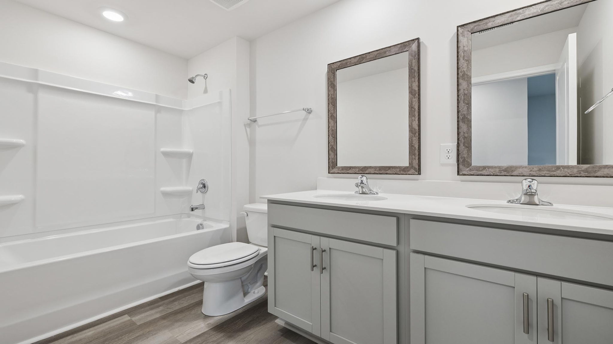 Hall bathroom with dual sink vanity and combination shower / tub.