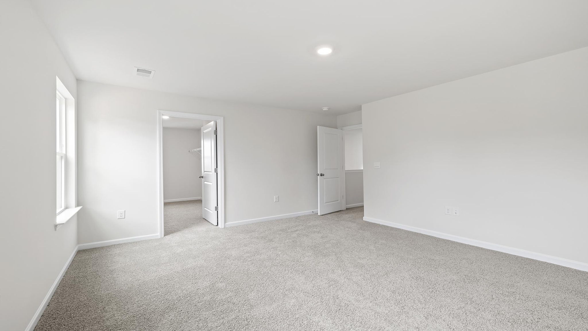 Primary bedroom with windows and carpet.
