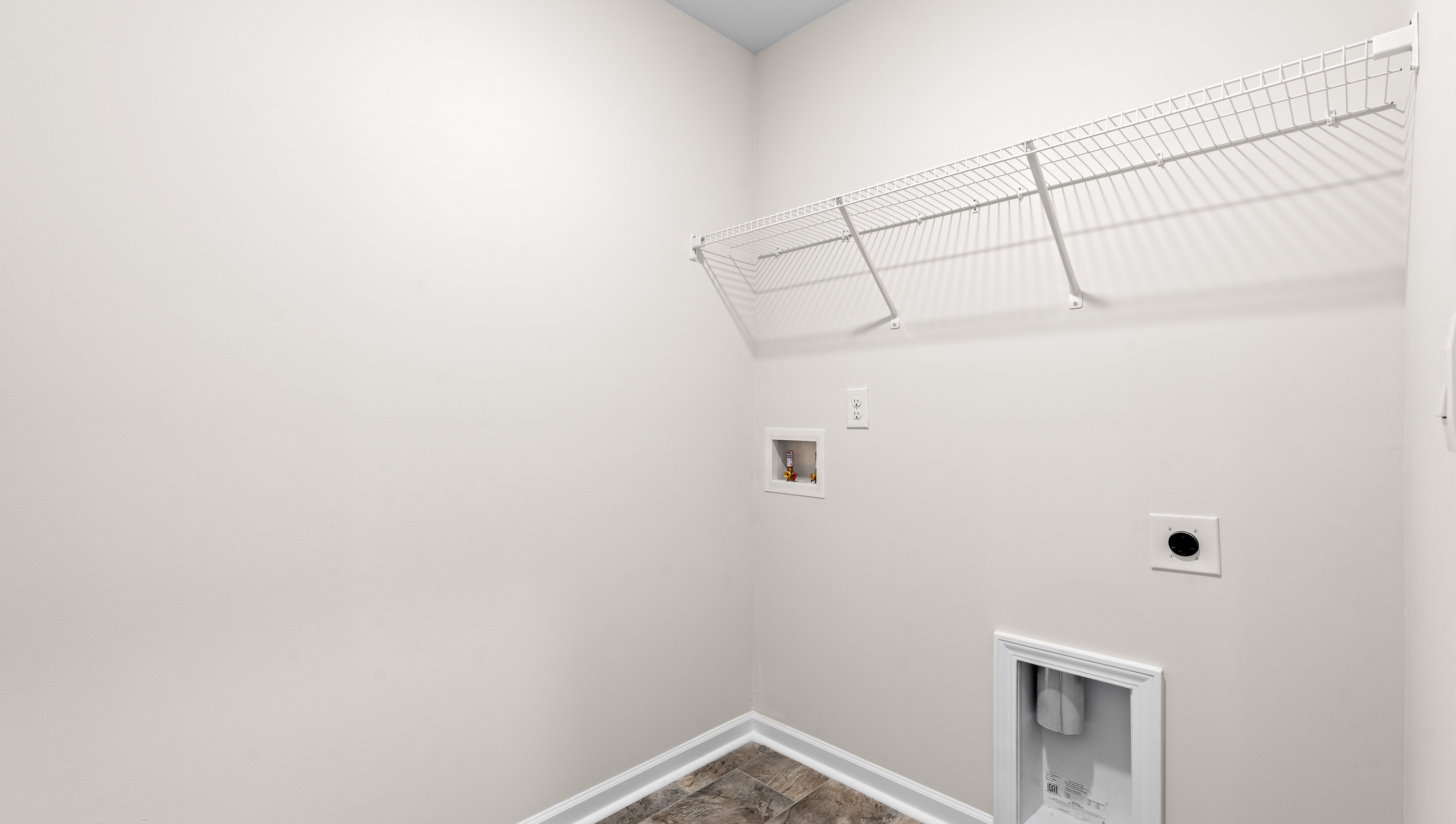 Laundry room with carpet and shelf.