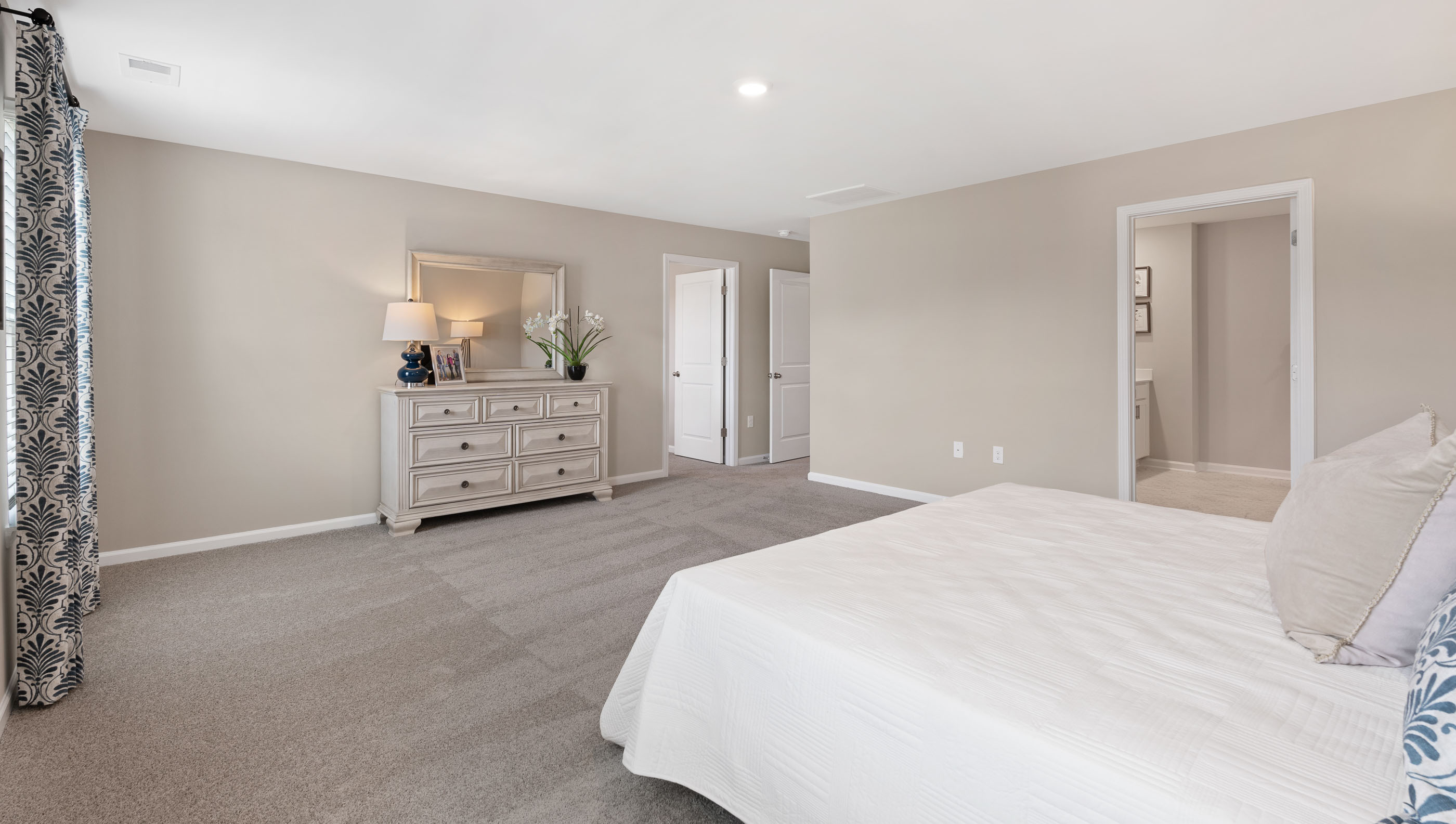 Primary bedroom with carpet and window.