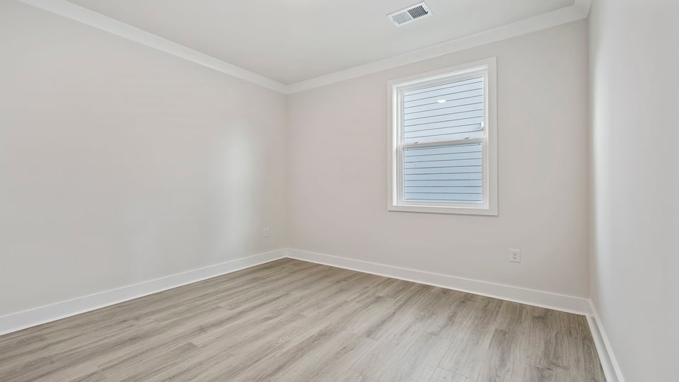 Bedroom with window and laminate flooring.