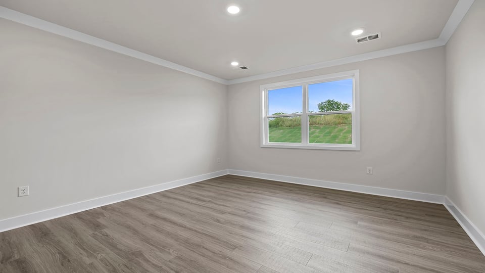 Primary bedroom with large window, recessed lighting and laminate flooring.
