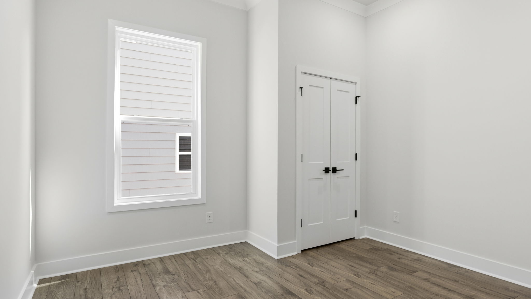Bedroom with window and laminate flooring.