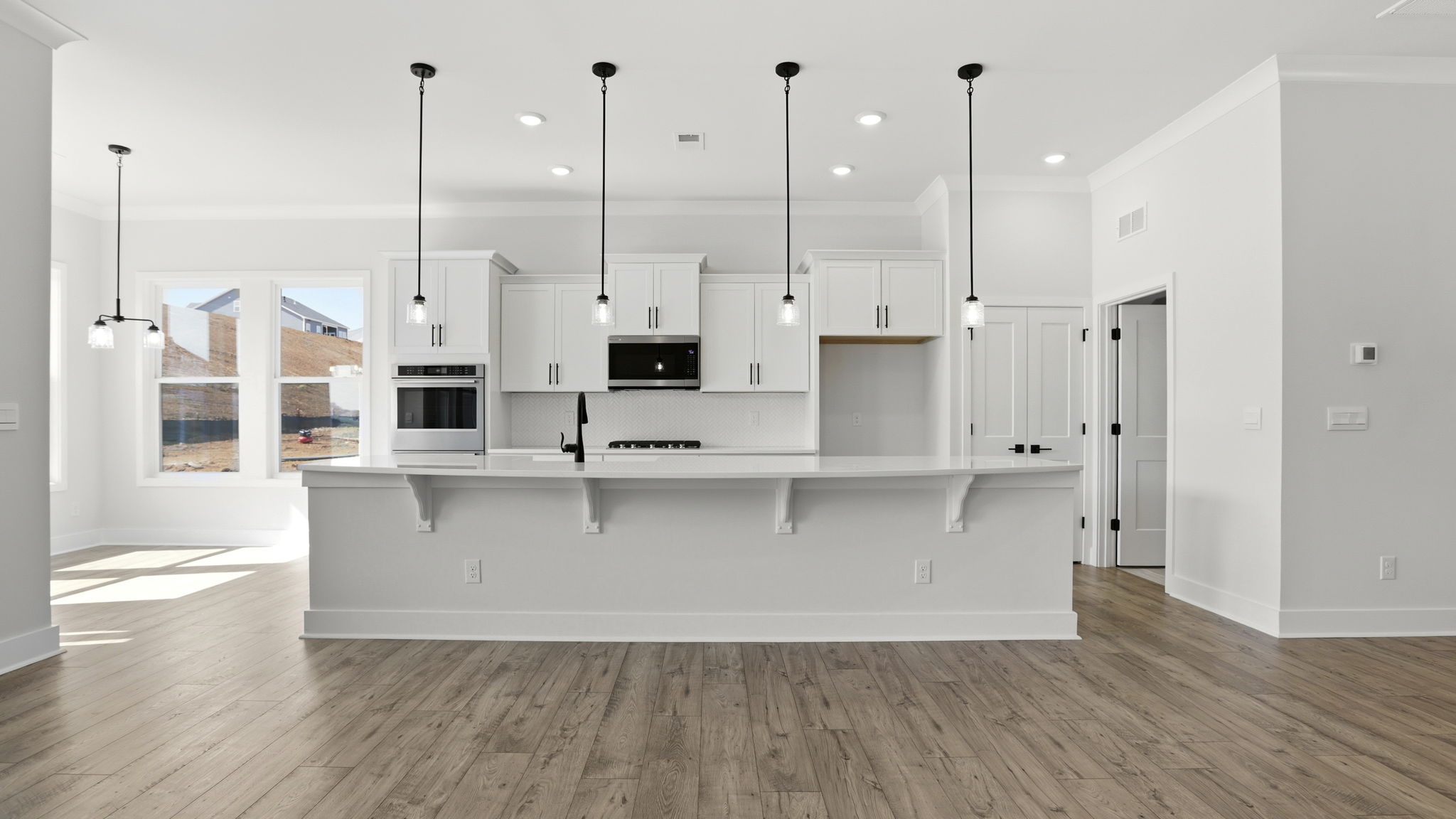View of the gourmet kitchen with pendulum lighting, island, and stainless steel appliances.