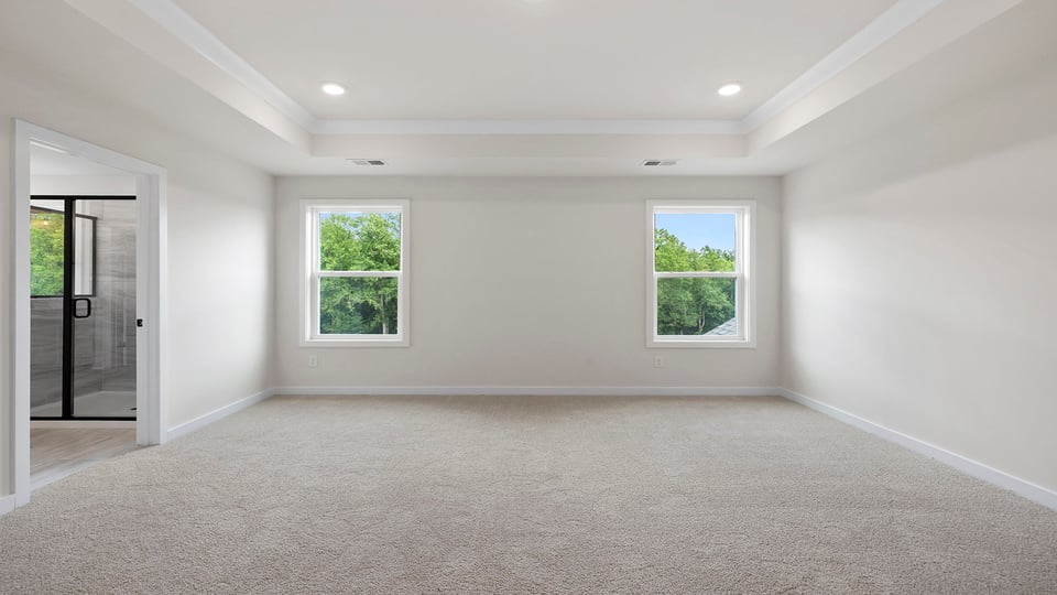 Primary bedroom with carpet and windows.