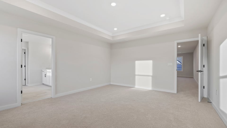 Primary bedroom with carpet and windows.