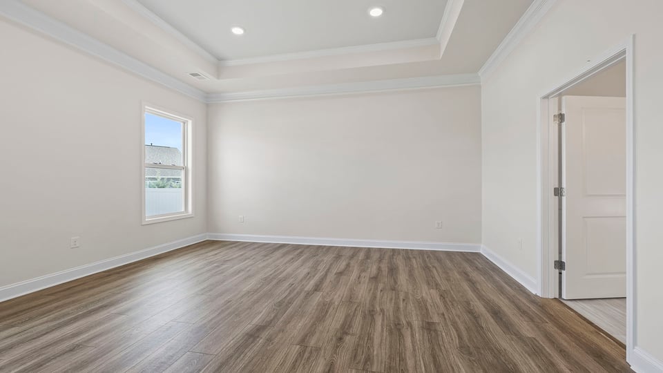 Primary bedroom with trey ceiling and recessed lighting.
