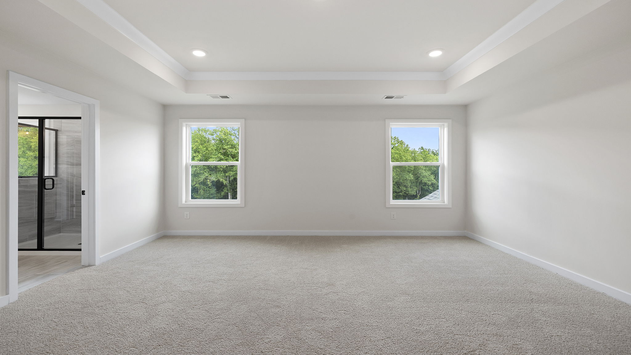 Primary bedroom with windows and carpet.