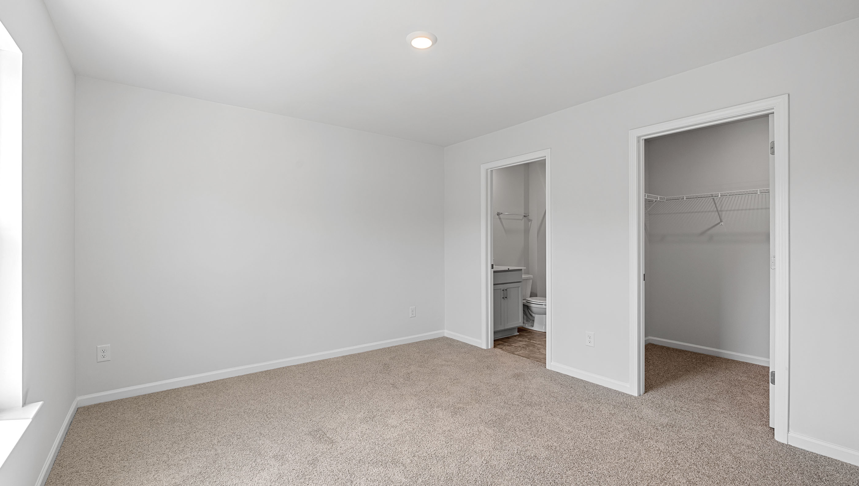 Primary bedroom with window and carpet.