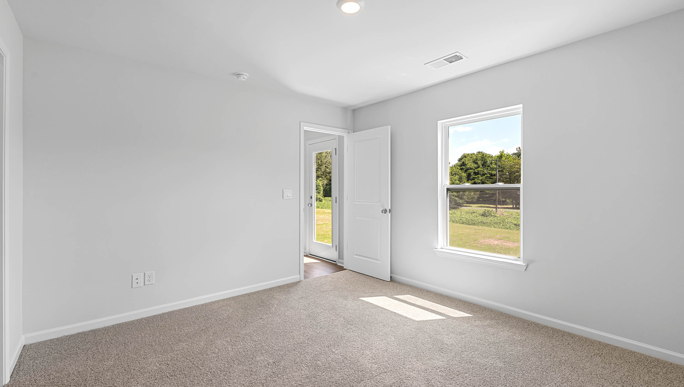 Primary bedroom with window and carpet.