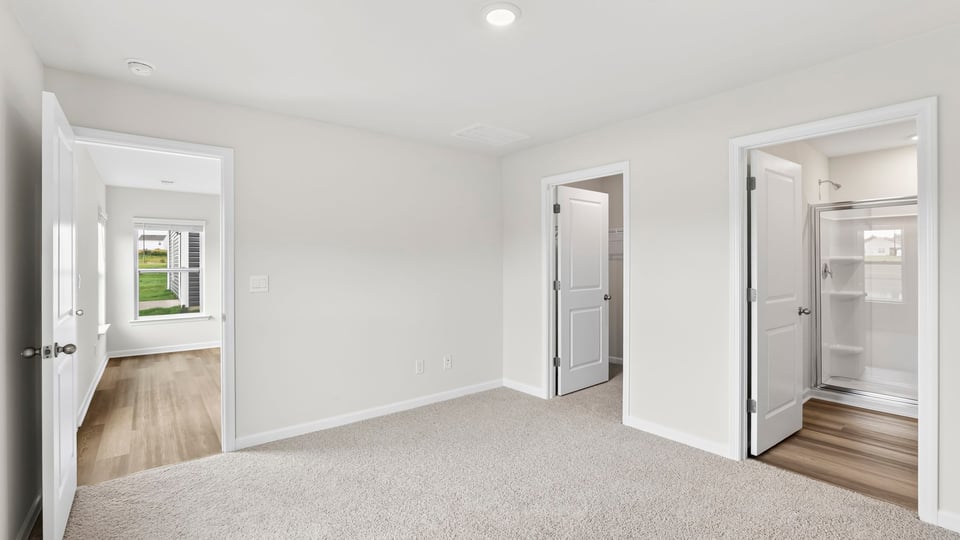 Primary bedroom with carpet and window.