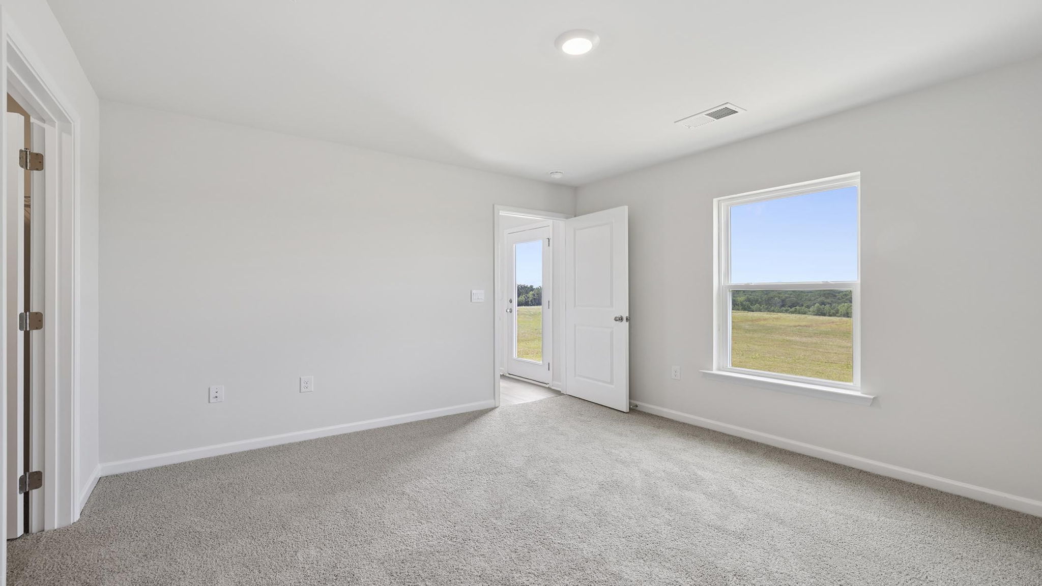 Primary bedroom with carpet and windows.