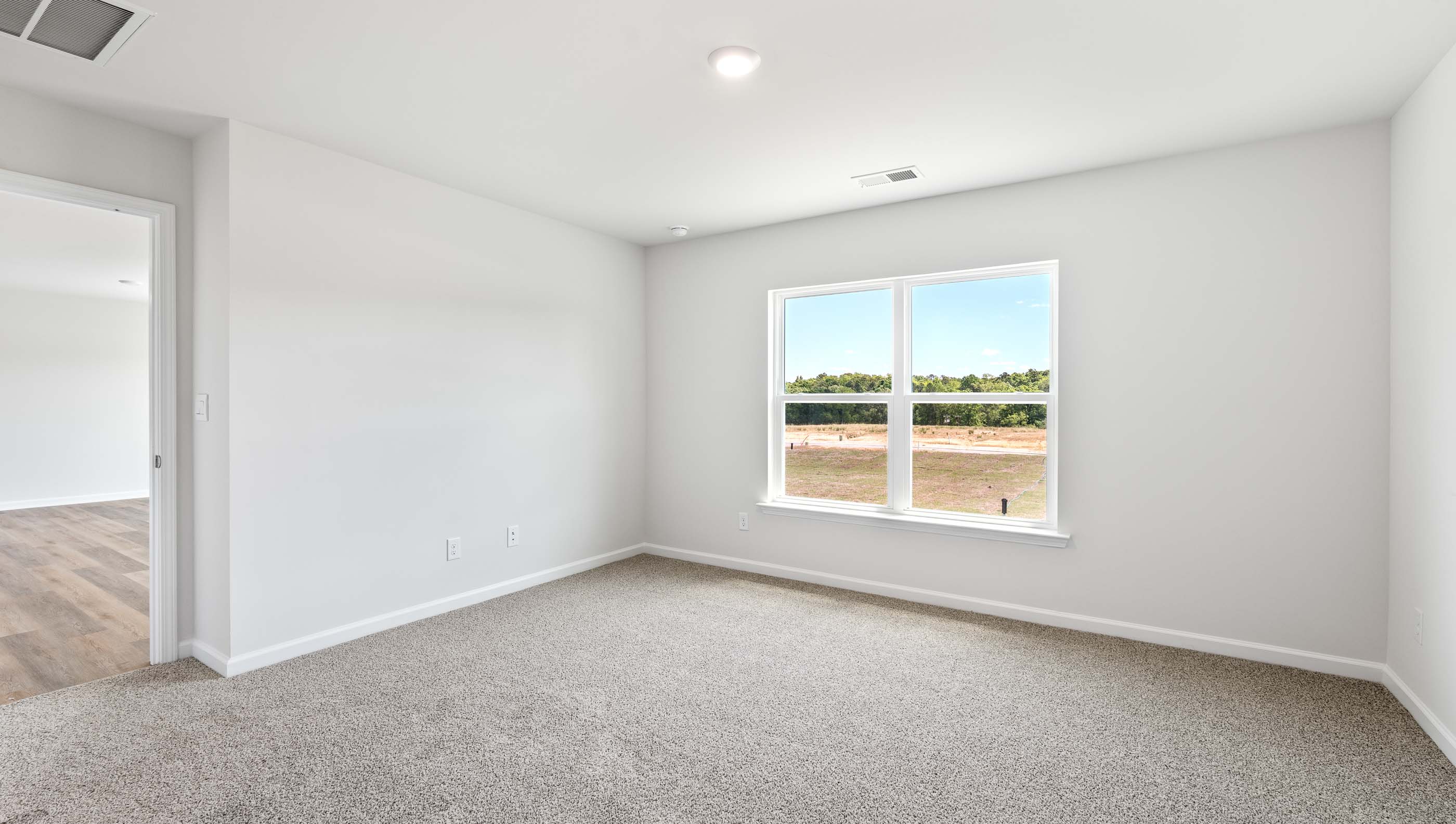 Primary bedroom with window and carpet.
